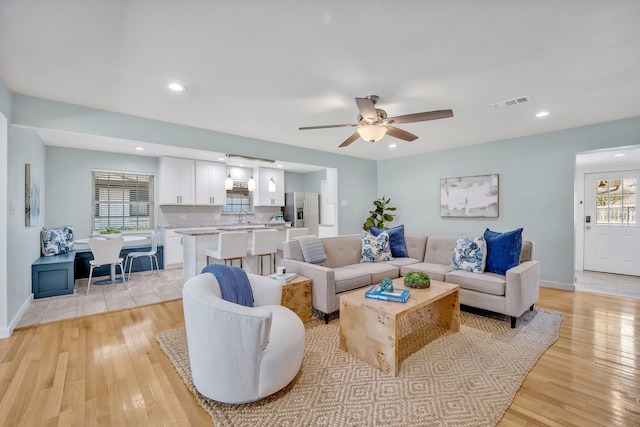 living area featuring recessed lighting, a ceiling fan, baseboards, visible vents, and light wood-style floors