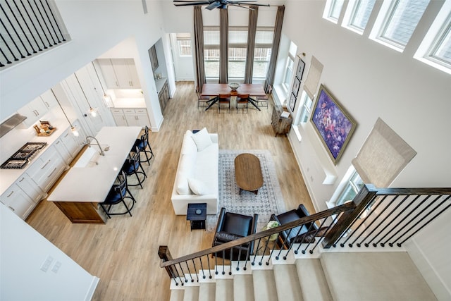 living area with stairway, light wood-style flooring, and a towering ceiling