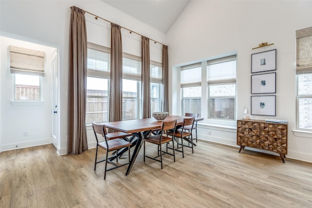 dining room with baseboards, lofted ceiling, and light wood-style flooring