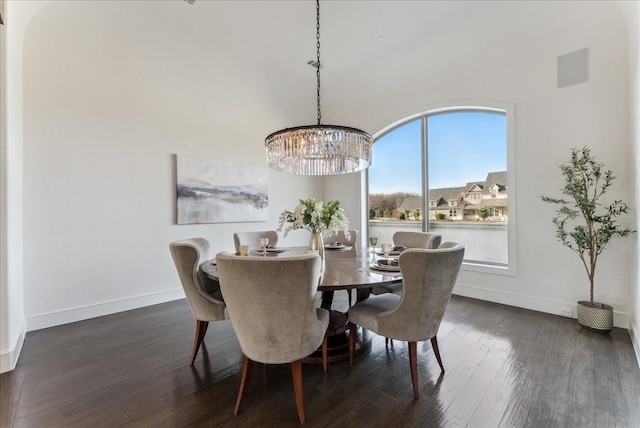 dining room featuring a notable chandelier, dark wood finished floors, and baseboards