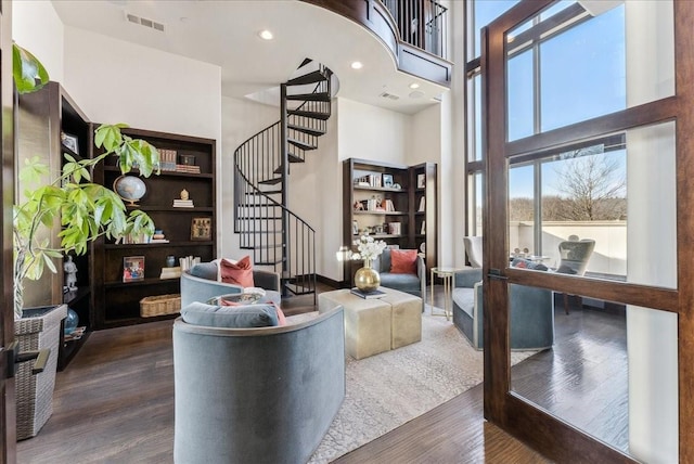 living area with stairs, visible vents, a towering ceiling, and wood finished floors