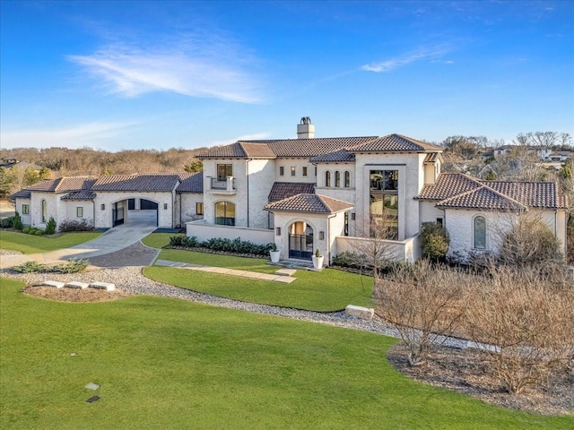 mediterranean / spanish home featuring a tile roof, a chimney, stucco siding, concrete driveway, and a front yard