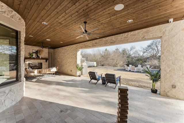 view of patio with an outdoor stone fireplace and a ceiling fan