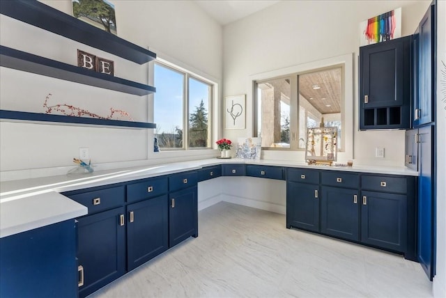 kitchen with open shelves, light countertops, and blue cabinets