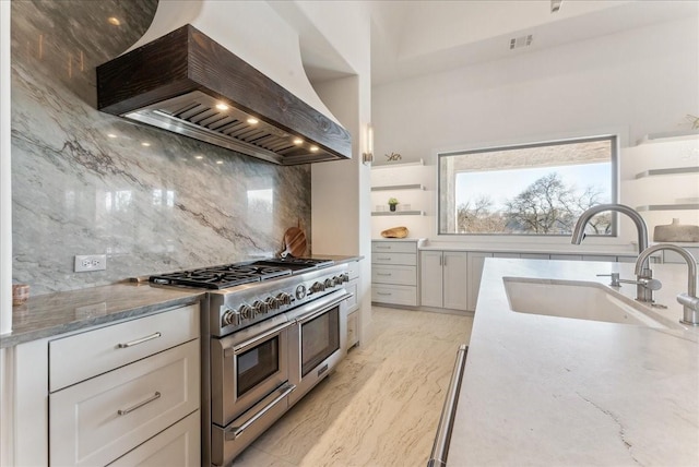 kitchen featuring light stone countertops, double oven range, custom range hood, and a sink