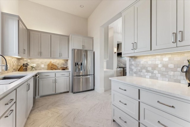 kitchen with tasteful backsplash, gray cabinetry, a sink, and stainless steel fridge with ice dispenser