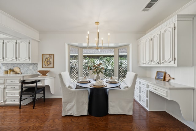 dining room featuring visible vents, dark wood finished floors, built in study area, ornamental molding, and a chandelier