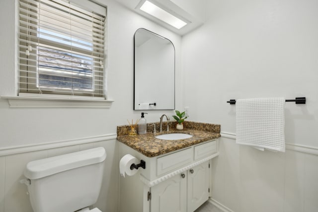 bathroom with toilet, a wainscoted wall, and vanity