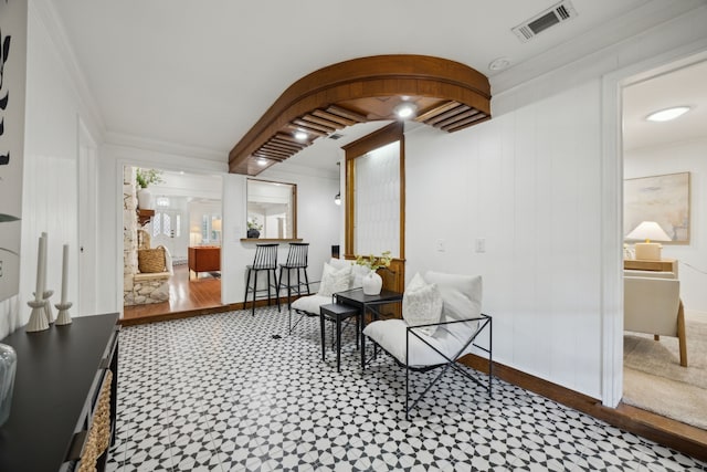 sitting room featuring ornamental molding, arched walkways, visible vents, and baseboards