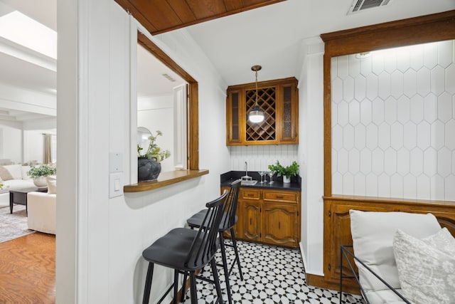 bar featuring wet bar, backsplash, visible vents, and decorative light fixtures