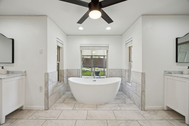 full bathroom with a freestanding tub, ceiling fan, marble finish floor, and two vanities