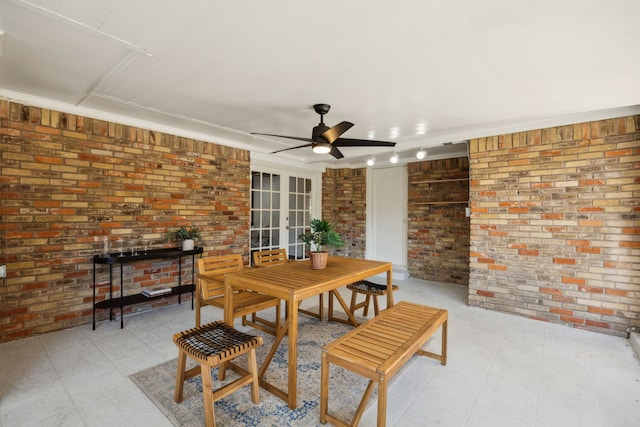 dining area featuring light floors, french doors, ceiling fan, and brick wall