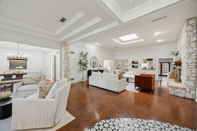 living area with a skylight, visible vents, a chandelier, and wood finished floors