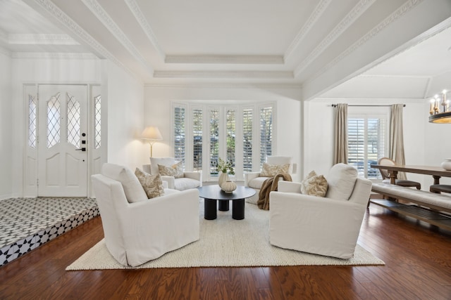 living area with wood-type flooring, a raised ceiling, crown molding, and an inviting chandelier