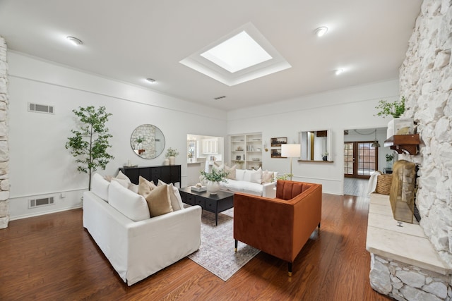 living area with built in shelves, a skylight, wood finished floors, and visible vents