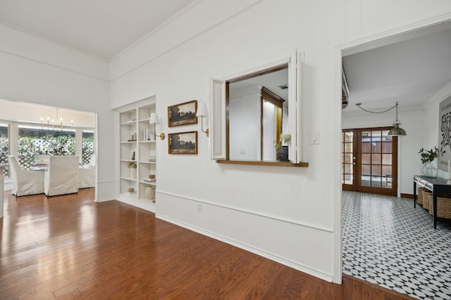 unfurnished room with a wealth of natural light, a notable chandelier, and wood finished floors