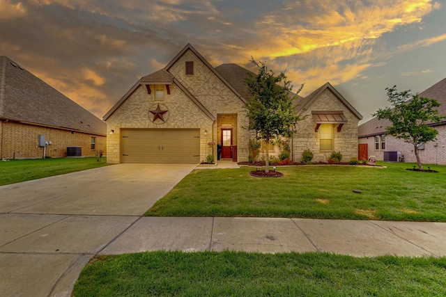 french country home with a garage, driveway, a front lawn, and central AC