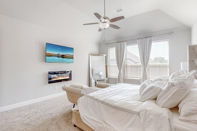 bedroom featuring visible vents, baseboards, a glass covered fireplace, carpet, and vaulted ceiling