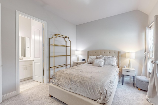 bedroom with lofted ceiling, baseboards, connected bathroom, and light colored carpet