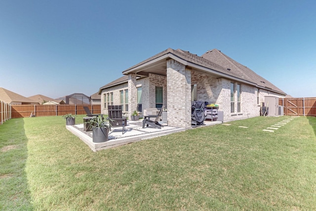 back of property with a patio, brick siding, a lawn, and a fenced backyard