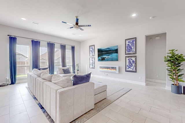 living area with light tile patterned floors, recessed lighting, baseboards, and a glass covered fireplace