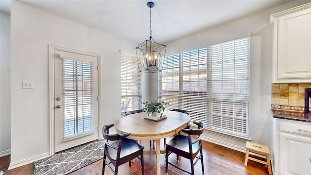 dining room featuring a chandelier, baseboards, and wood finished floors