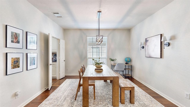 dining space featuring a notable chandelier, dark wood finished floors, visible vents, and baseboards