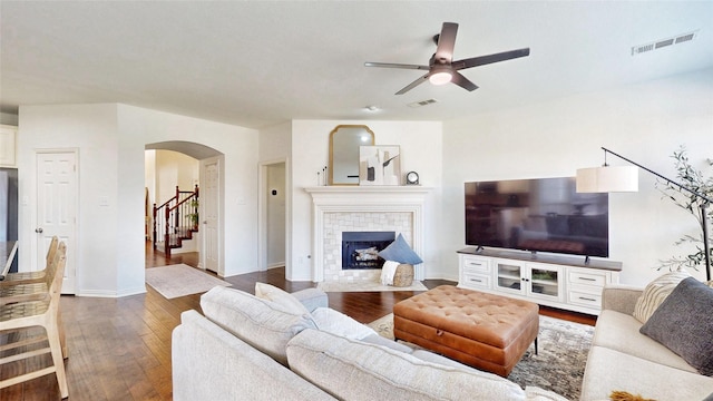 living area with arched walkways, wood-type flooring, a fireplace, and visible vents