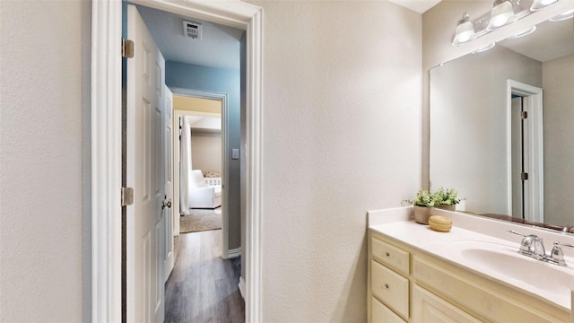 bathroom featuring visible vents, a textured wall, vanity, and wood finished floors