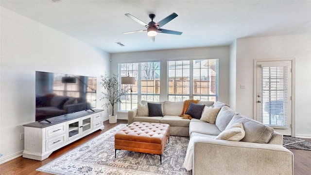 living area with dark wood-style floors, ceiling fan, visible vents, and baseboards