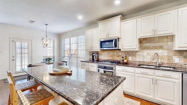 kitchen featuring stainless steel appliances, visible vents, a sink, and tasteful backsplash