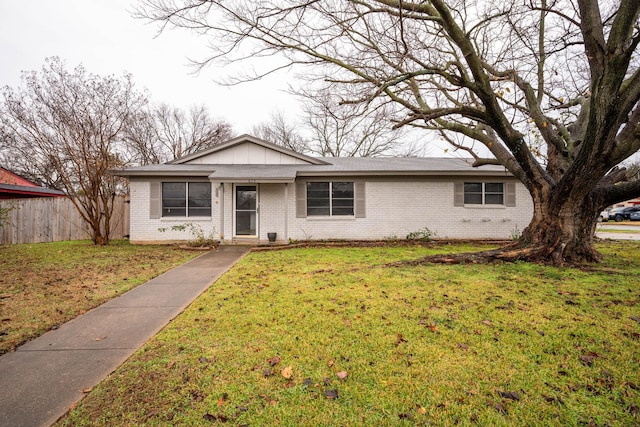 ranch-style house with board and batten siding, a front yard, brick siding, and fence