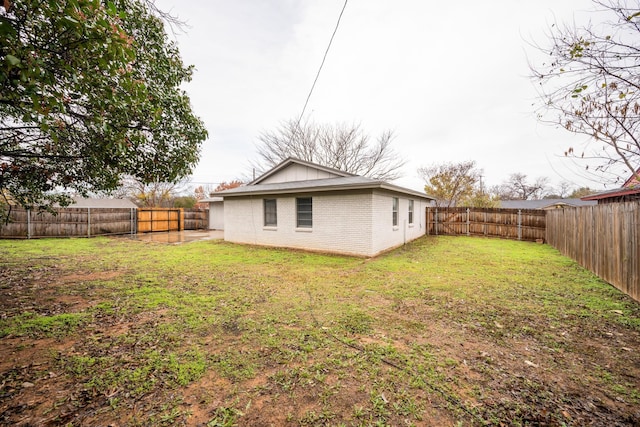 back of property featuring brick siding, a lawn, and a fenced backyard