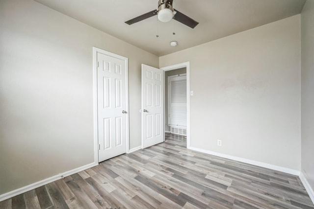 unfurnished bedroom with ceiling fan, a closet, baseboards, and wood finished floors