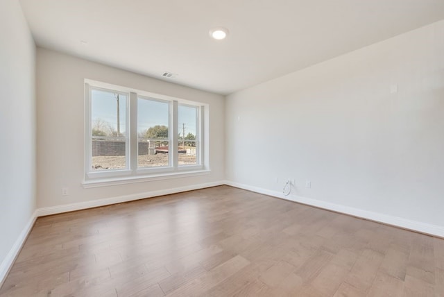 spare room featuring baseboards, visible vents, and wood finished floors