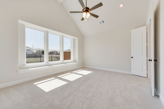 empty room with high vaulted ceiling, baseboards, visible vents, and light colored carpet