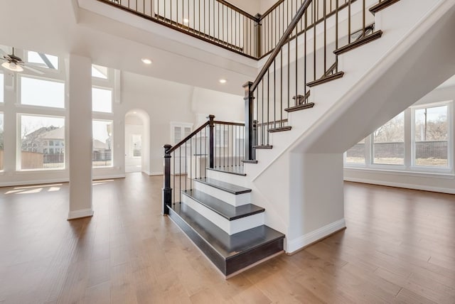 stairs with a high ceiling, wood finished floors, and baseboards