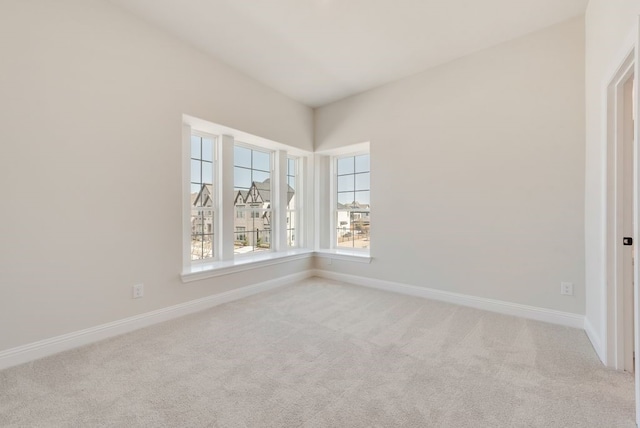 empty room with baseboards and light colored carpet