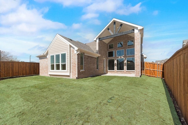 rear view of house with brick siding, a yard, and a fenced backyard