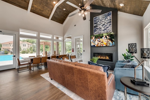 living room with high vaulted ceiling, wooden ceiling, a fireplace, wood finished floors, and beamed ceiling