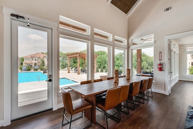 dining room with visible vents, dark wood-type flooring, ceiling fan, high vaulted ceiling, and baseboards