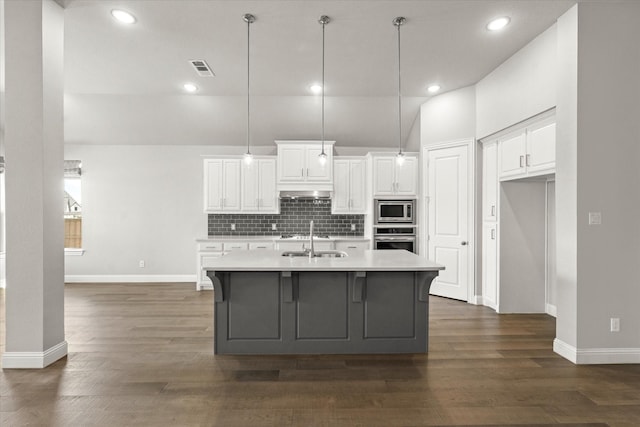 kitchen with tasteful backsplash, appliances with stainless steel finishes, dark wood finished floors, and a sink