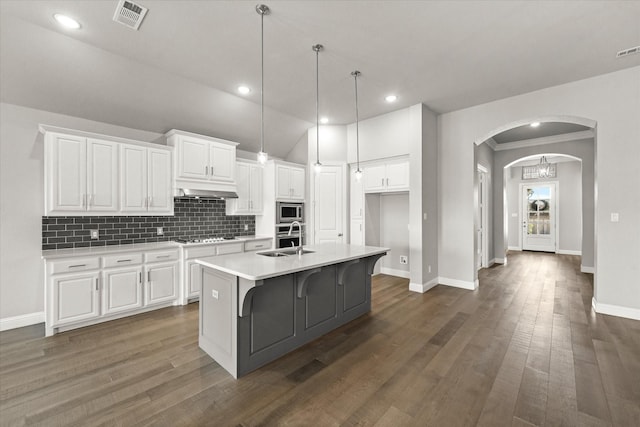 kitchen with arched walkways, visible vents, appliances with stainless steel finishes, white cabinets, and a sink