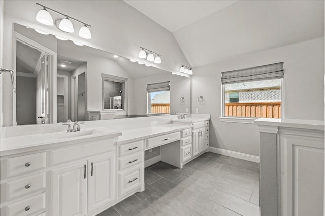 full bath featuring lofted ceiling, a sink, baseboards, and double vanity