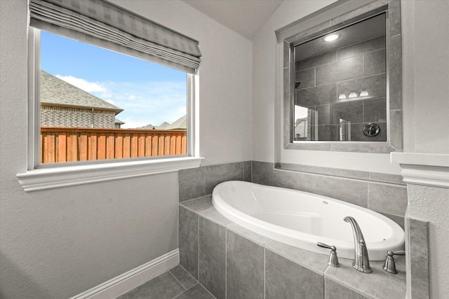 full bath featuring tile patterned flooring, a garden tub, a tile shower, and baseboards