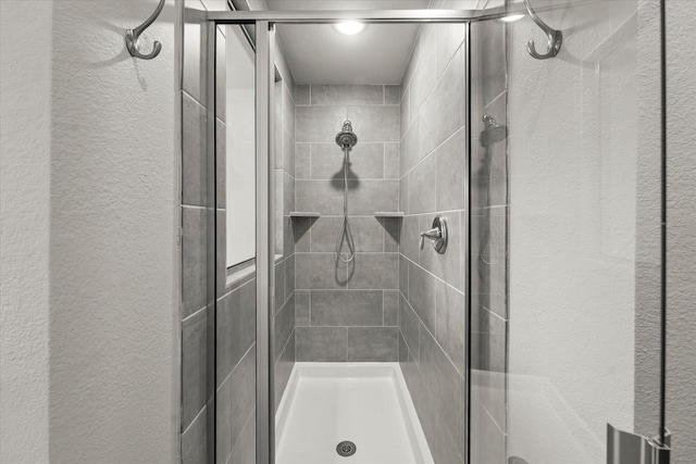 bathroom featuring a textured wall and a stall shower