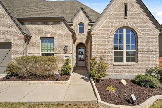 view of front facade with a shingled roof and brick siding