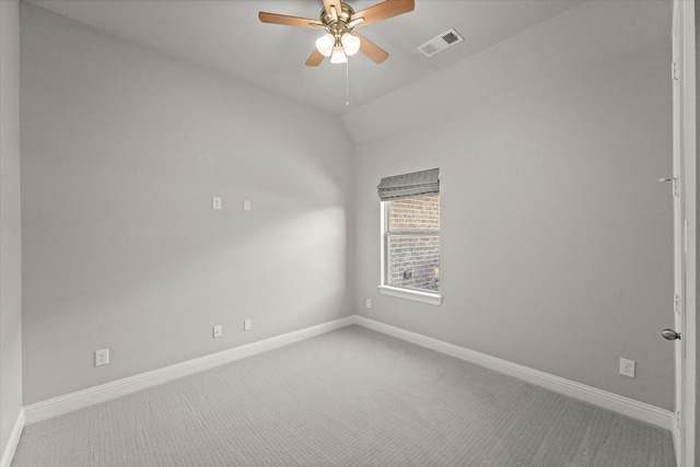 carpeted spare room with lofted ceiling, visible vents, ceiling fan, and baseboards