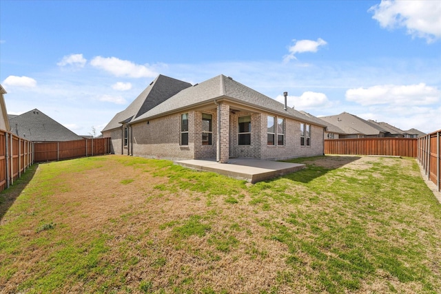 rear view of property with a patio area, a yard, a fenced backyard, and brick siding