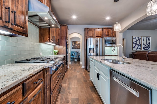 kitchen with a sink, stainless steel appliances, arched walkways, extractor fan, and dark wood-style flooring